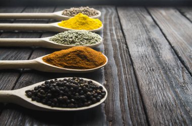 siyah ahşap zemin tahta kaşıklar içinde farklı baharatlar