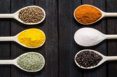 siyah ahşap zemin tahta kaşıklar içinde farklı baharatlar