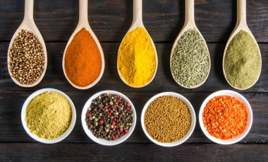 siyah ahşap zemin tahta kaşıklar içinde farklı baharatlar