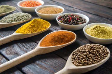 siyah ahşap zemin tahta kaşıklar içinde farklı baharatlar