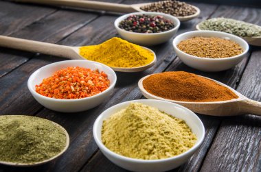 siyah ahşap zemin tahta kaşıklar içinde farklı baharatlar