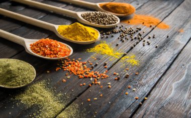 siyah ahşap zemin tahta kaşıklar içinde farklı baharatlar