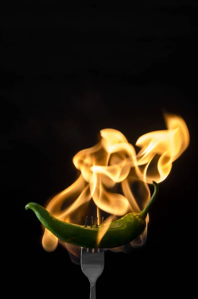 フォークの炎で黒の背景に緑のホット ペッパー — ストック写真