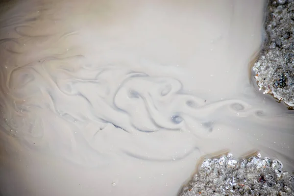A stream of muddy dirty water with swirls.