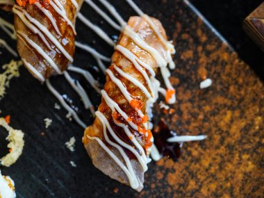 Üzerinde mayonez ve ebiko olan kurutulmuş wagyu bifteği suşisi siyah taş bir tabakta servis edilir. Japon Mutfak Büfesi.