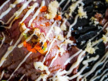 Siyah taş tabakta servis edilen mayonez, ebiko ve kaz ciğeri soslu Jumbo wagyu sığır suşisi. Japon Mutfak Büfesi.