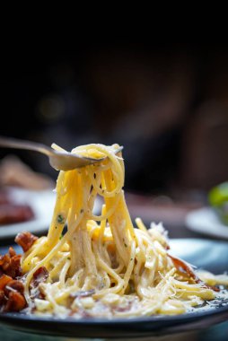 Spagetti, çatalla kayan lezzetli bir makarna. Yumurta, sert peynir, guanciale, pastırma ve karabiberden yapılmış Carbonara. Yiyecek Arkaplanı.