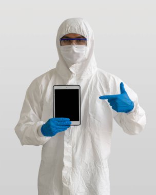 Virüse karşı koruyucu giysi giyen epidemiyolojik araştırmacılar ellerinde boş tablet bilgisayar tutuyorlar..