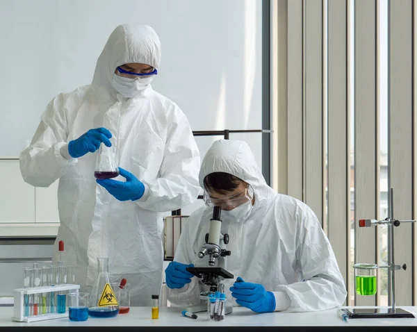 Araştırmacılar mikrop kapmış insanların kan örneklerine bakmak için mikroskop kullanıyorlar.