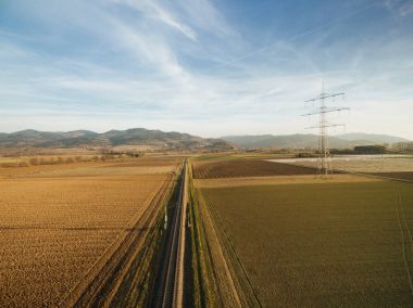 aerial view of electricity tower in agricultural fields on sunset, europe clipart