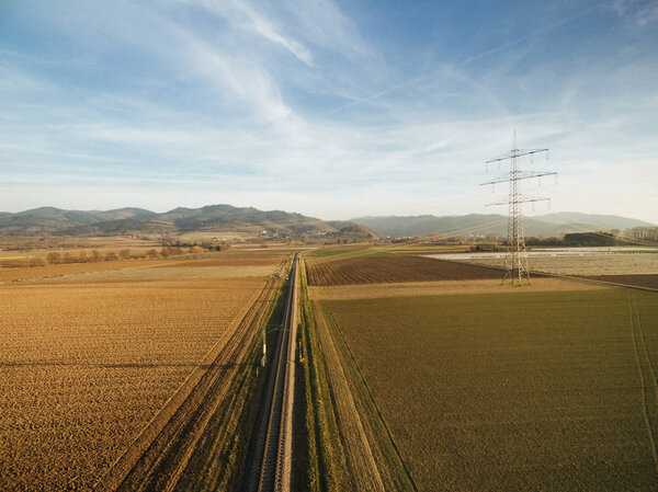 aerial view of electricity tower in agricultural fields on sunset, europe