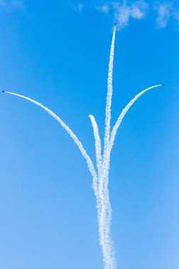Bir grup savaşçı açık güneşli bir askeri uçak profesyonel pilotlar hileler mavi gökyüzünde bulutlar güzel izler bırakarak farklı yönlere dağınık gösterir.