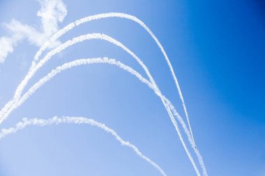 Bir grup savaşçı açık güneşli bir askeri uçak profesyonel pilotlar hileler mavi gökyüzünde bulutlar güzel izler bırakarak farklı yönlere dağınık gösterir.