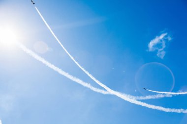 Bir grup savaşçı açık güneşli bir askeri uçak profesyonel pilotlar hileler mavi gökyüzünde bulutlar güzel izler bırakarak farklı yönlere dağınık gösterir.