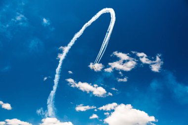 Bir grup savaşçı açık güneşli bir askeri uçak profesyonel pilotlar hileler mavi gökyüzünde bulutlar güzel izler bırakarak farklı yönlere dağınık gösterir.