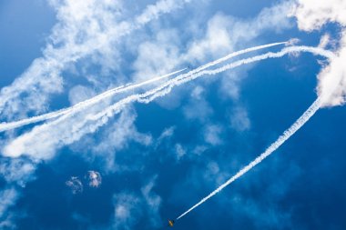 Bir grup savaşçı açık güneşli bir askeri uçak profesyonel pilotlar hileler mavi gökyüzünde bulutlar güzel izler bırakarak farklı yönlere dağınık gösterir.