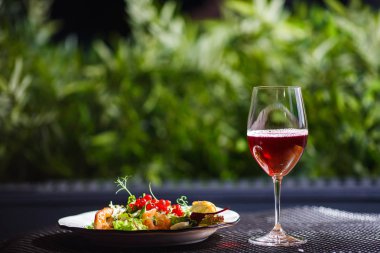 Bir bardak şarap bir içkiyle masaya bir tabak güzel iştah açıcı salata taze sebze, karides, bıldırcın yumurtası ve lingonberries olduğunu.