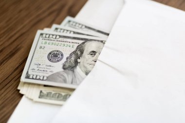 Benjamin Franklin zarf dışında görünüyor sanki Amerikan yüz dolarlık bir paket masanın üzerinde beyaz bir zarf içinde yer alır.