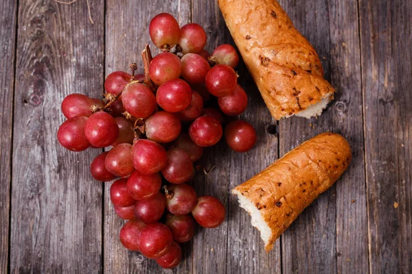 A bunch of juicy large red grapes and fresh crispy wheaten bague — Stock Photo, Image