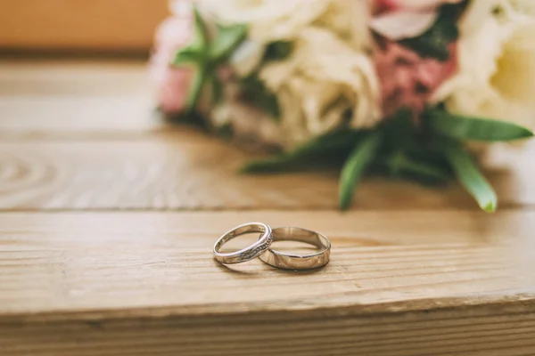 Kroužky na dřevěné podlaze s svatební květiny — Stock fotografie