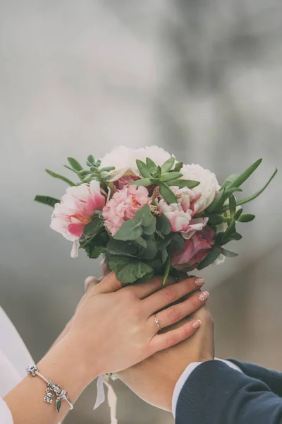 Boeket met bruiloft ringen in twee handen — Stockfoto