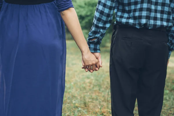 青いドレスの公園で手を繋いでいるカップル — ストック写真