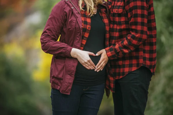 Pregnant couple holding hands on the belly iin heart — Stock Photo, Image