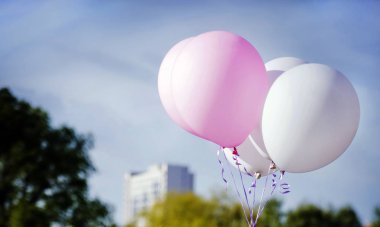 Beyaz ve pembe balonlar içinde ağaçları ile mavi gökyüzü 