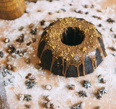 black  cake on the wooden table with nuts and powdered sugar and flour