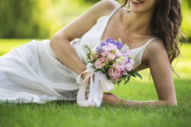 damat düğün buket bej ve pembe mor lila mor beyaz gelinlikle çimenlerin üzerinde ile döşeme