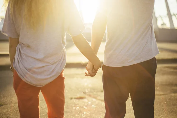 Lovely couple with red and dark jeans hold their hands  and look at the sun