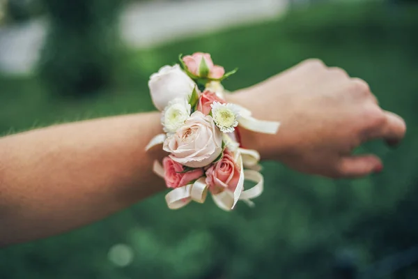 floral bracelet with roses beige and pink and purple and white on the hand grass background