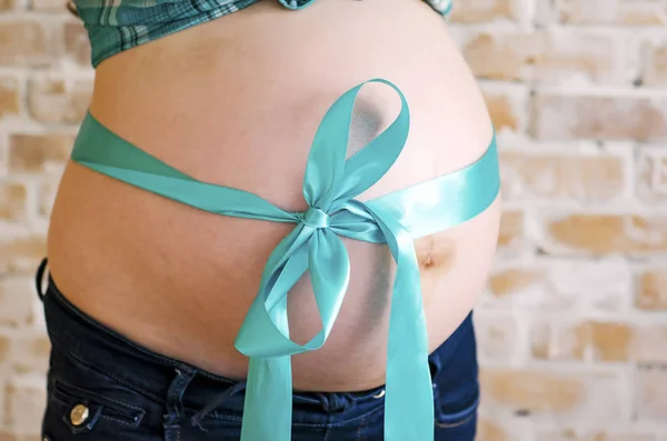 Ventre de femme enceinte avec du ruban turquoise — Photo