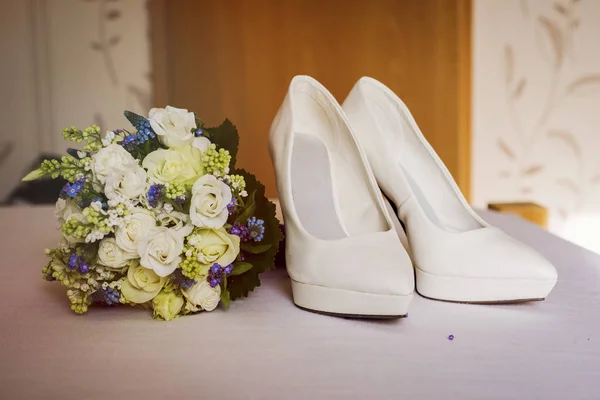 Wedding bouquet with shoes on the bad near  the door — Stock Photo, Image