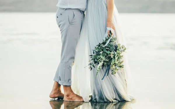 Bröllop brudgum stående i vattnet med bukett kramas — Stockfoto