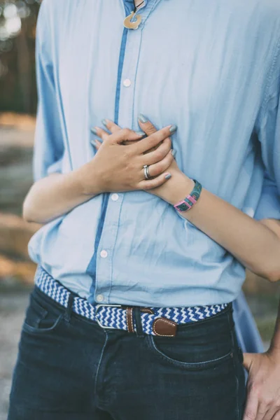 woman is hugging her man with hands and watch