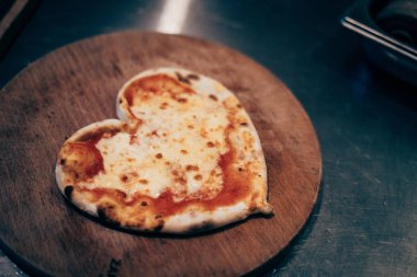 Kalp şeklinde bir pizza fırından yuvarlak bir tahta üzerinde.