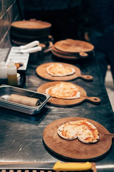 Три пиццы в форме сердца на кухонном столе, готовые к выпечке — стоковое фото