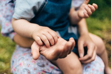Bir çocuğun eli ve bir yetişkinin eli. Bebek, elini annesinin avucuna koydu. Çocuk kolu ve ebeveynin kolu..
