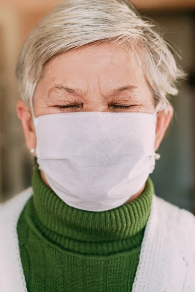 Senior woman wearing face mask during corona virus and flu outbreak. Disease and illness protection. Surgical masks for coronavirus prevention. Sick elderly patient coughing. Close up.