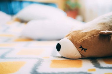 Yumuşak tüylü bir ayı oyuncağı yatağın üzerindeki sarı bir yatak örtüsünün üzerinde yatıyor. Güneşli bir gün. Tembel ruh hali. Evde uykulu bir halde. Beklemede kal. Çocuklar ve yetişkinler için oyuncaklar. Virüs yüzünden bahar geldi. Kapat.