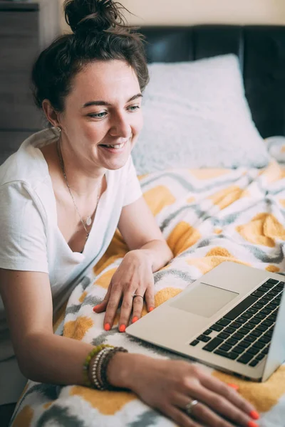 A young woman talking online with face time on a laptop. Fun mood. Happy morning Joyful communication with relatives and friends online. Expression of emotions. Stay home concept.