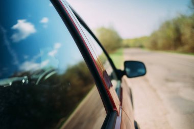 Aynalı arabanın yansıması mavi gökyüzünde yol alıyor.