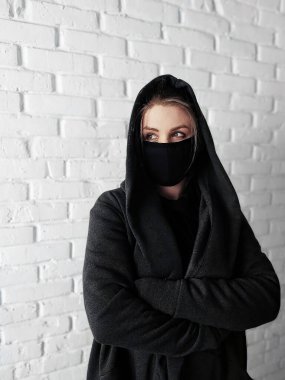 Moda tarzı, siyah tıbbi maskeli, beyaz arka planlı, sıkıntılı genç bir kadın. Coronavirus covid 19 salgın hastalık konsepti. İnsanlar korunmak için maske takıyor. Kapat.