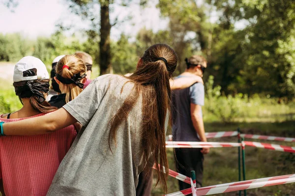 Una chica cercana está de pie con su espalda y lidera un equipo de personas con los ojos vendados . — Foto de Stock