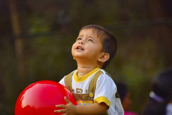 Lindo bebé jugando con bola roja en el jardín, Pune, Maharashtra . — Foto de Stock