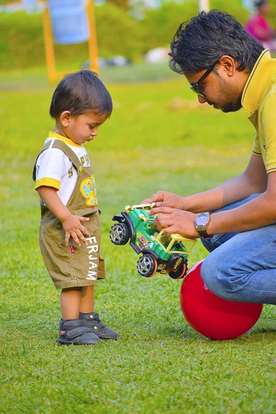 Lindo bebé jugando con coche de juguete y papá, Pune, Maharashtra . — Foto de Stock