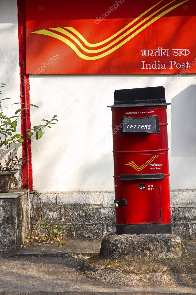 Red letter box with background of India Post, Pune University campus at Pune