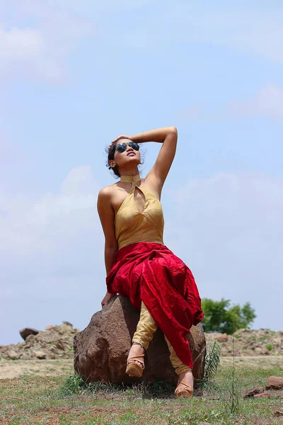 Jonge vrouw poseren zittend op een rotsblok — Stockfoto