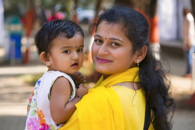 Young woman with her daughter smiling at camera, Empress garden, Pune clipart